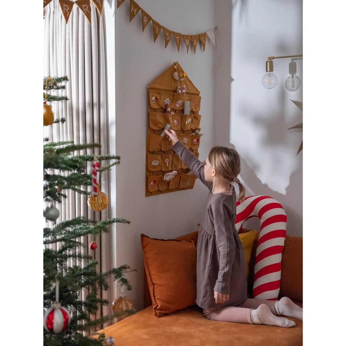 Kind am Adventskalender in senfgelb, weihnachtlich dekoriertes Kinderzimmer, Weihnachtsbaum
