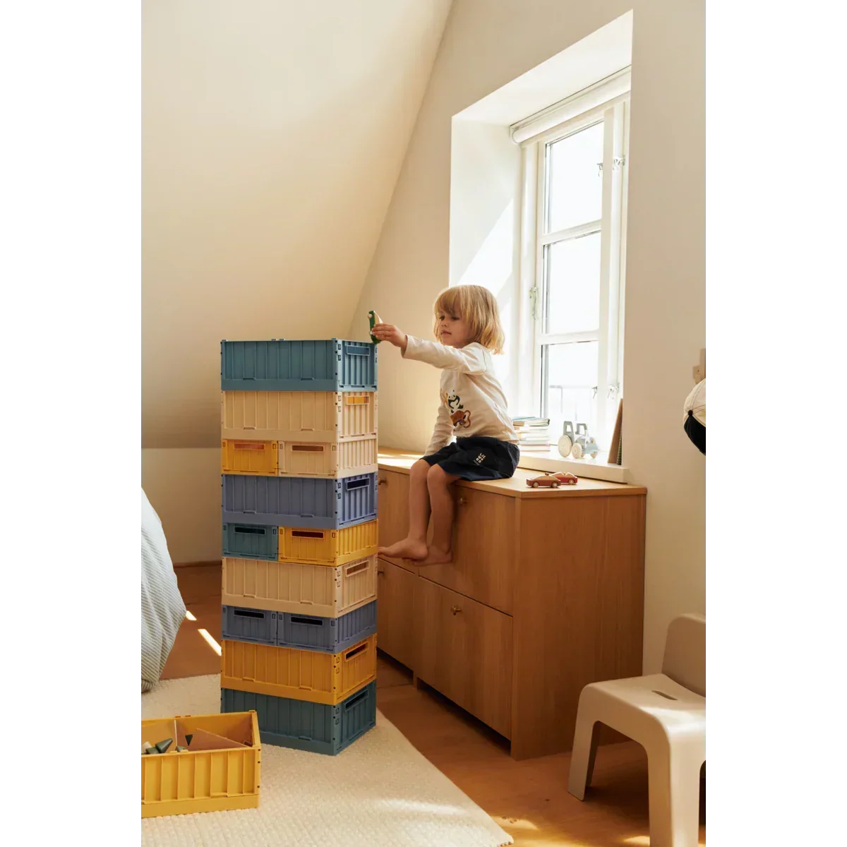 Kind im Kinderzimmer spielt mit bunten Aufbewahrungsboxen, nachhaltige Kinderzimmer Dekoration