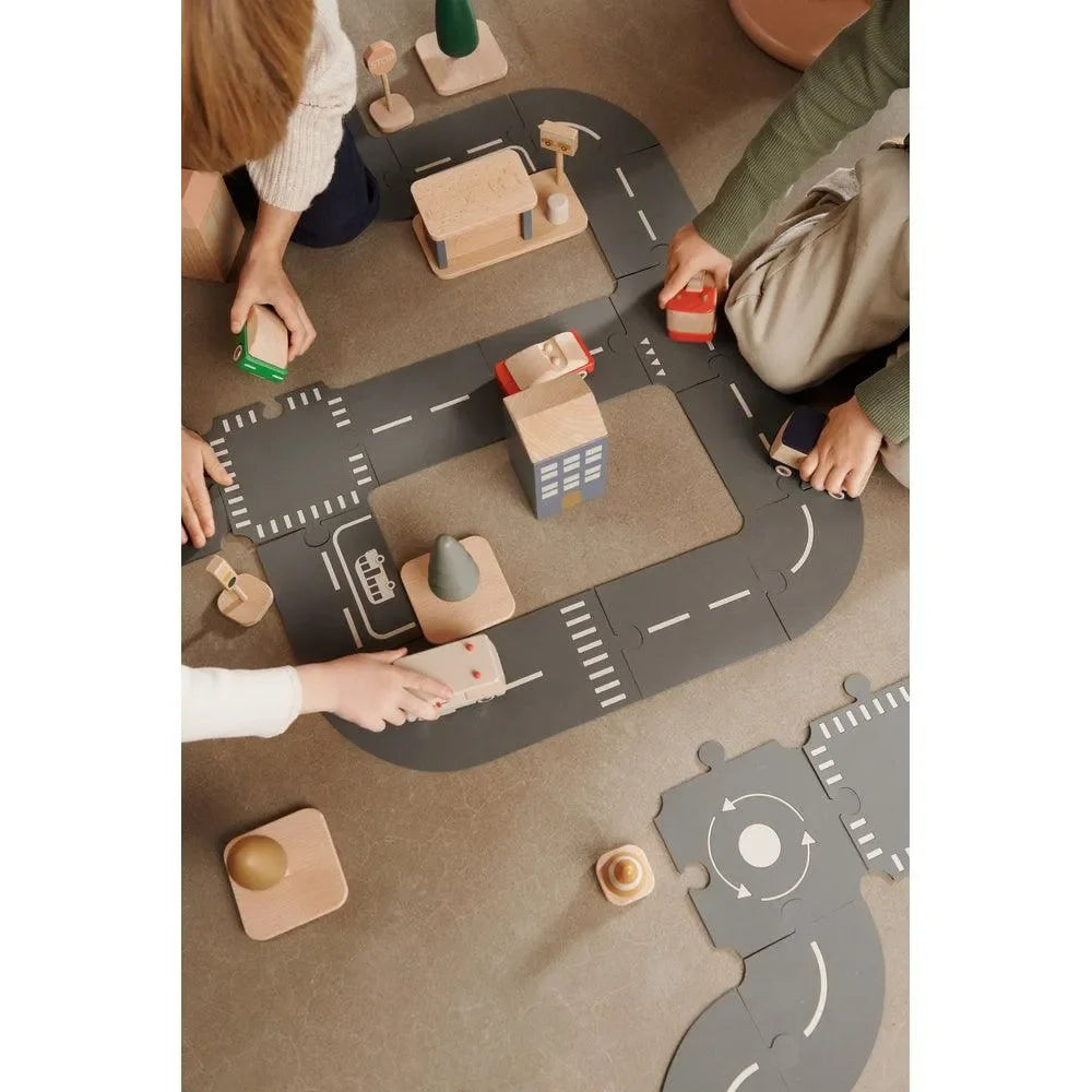 Kinder spielen mit Holzspielzeugautos und Straßenset im Kinderzimmer auf dem Boden
