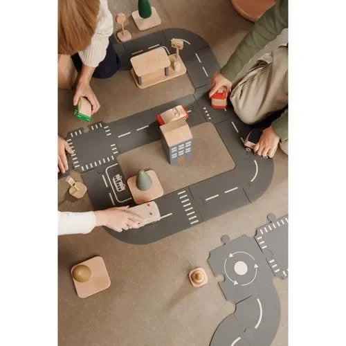 Kinder spielen mit Holzautos und Straßenset auf Spielmatte im Kinderzimmer