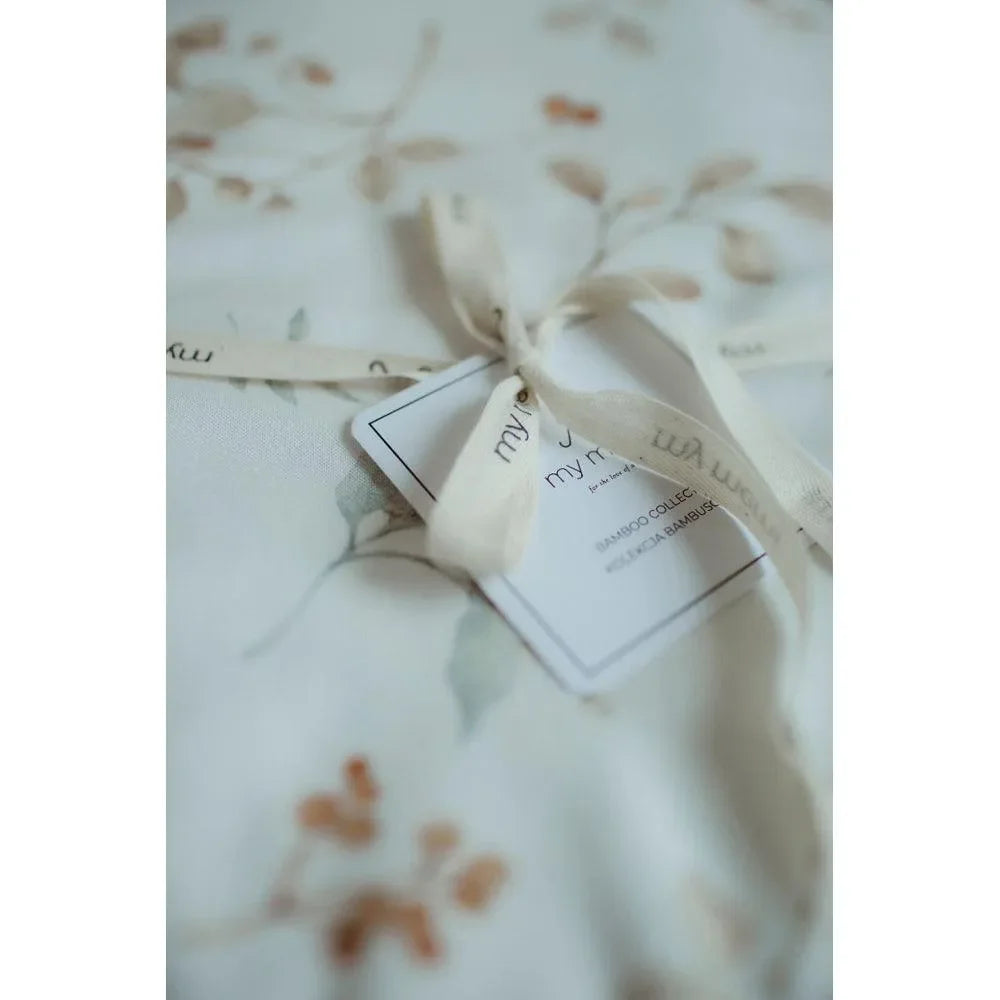 Weiche Bambus-Wickeldecke in Boho-Optik mit zartem Blumenmuster und Schleifenband.