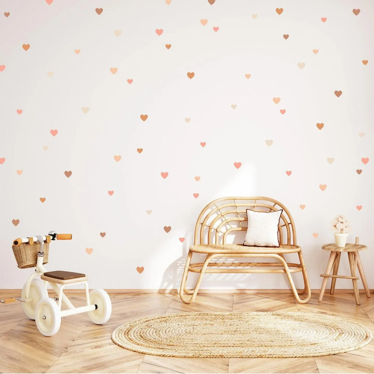 Kinderzimmer mit Herz-Wandtattoos, Rattan-Bank, Dreirad und Teppich auf Holzfußboden