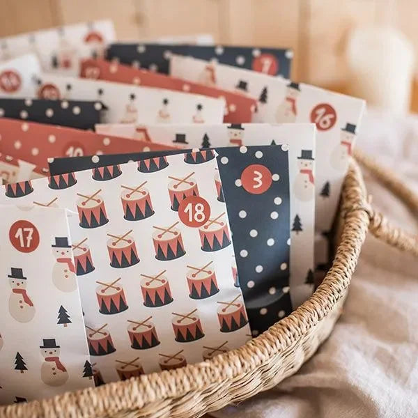 Adventskalender Tüten im Korb mit Weihnachtsmotiven wie Schneemann, Trommel und Häuser