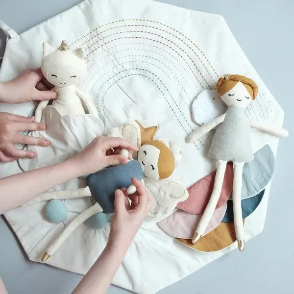 Kinder spielen mit Stoffpuppen und bunter Spielmatte mit Regenbogen-Motiv.