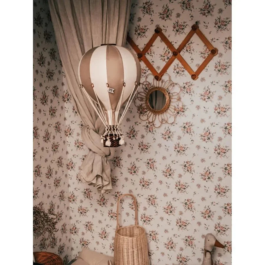 Heißluftballon Deko für Kinderzimmer vor geblümter Tapete und Rattan-Accessoires
