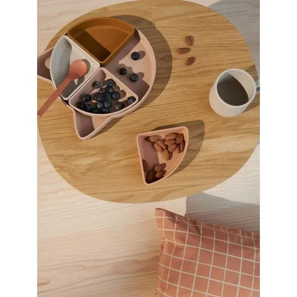 Geteilter Kinderteller in Katzenform aus Silikon, gefüllt mit Snacks und Löffel, auf Holztisch