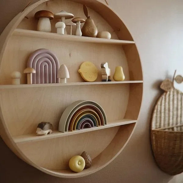 Rundes Holzregal mit Regenbogen Stapelspielzeug, Deko-Pilzen und Naturaccessoires im Kinderzimmer.