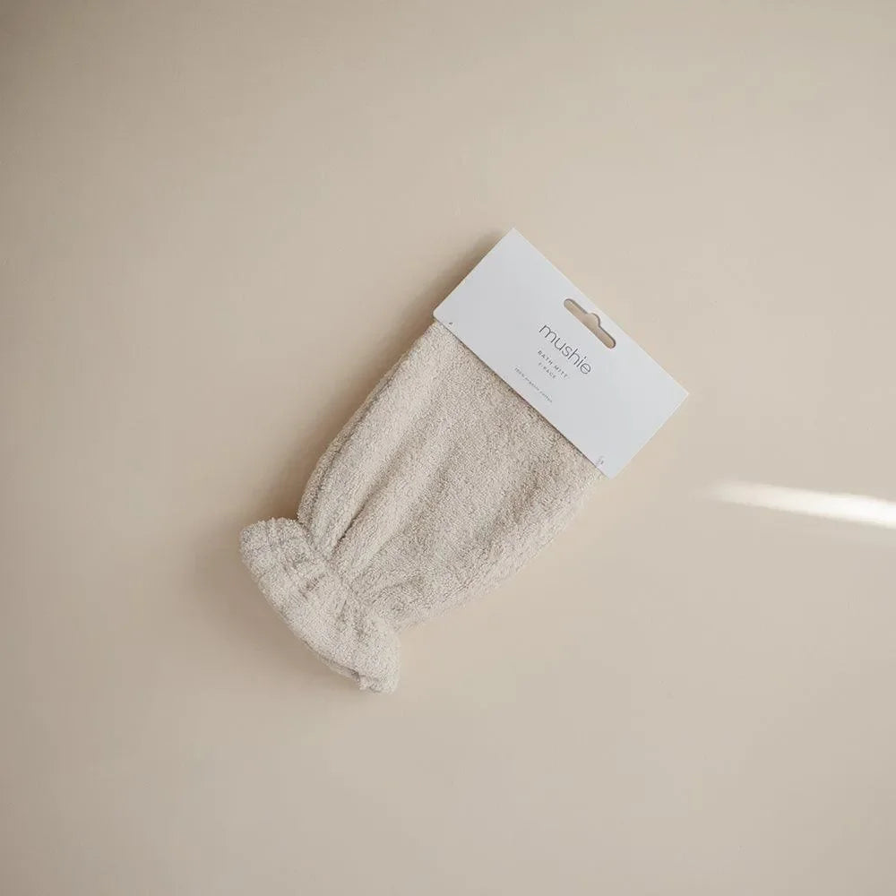 Beiger Baby-Waschhandschuh aus Frottee auf hellem Untergrund, umweltfreundlich, Badaccessoire