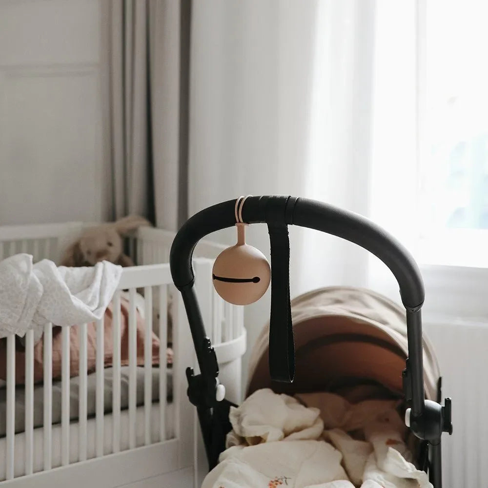 Beige Schnullerbox aus Silikon am Kinderwagen im gemütlichen Babyzimmer