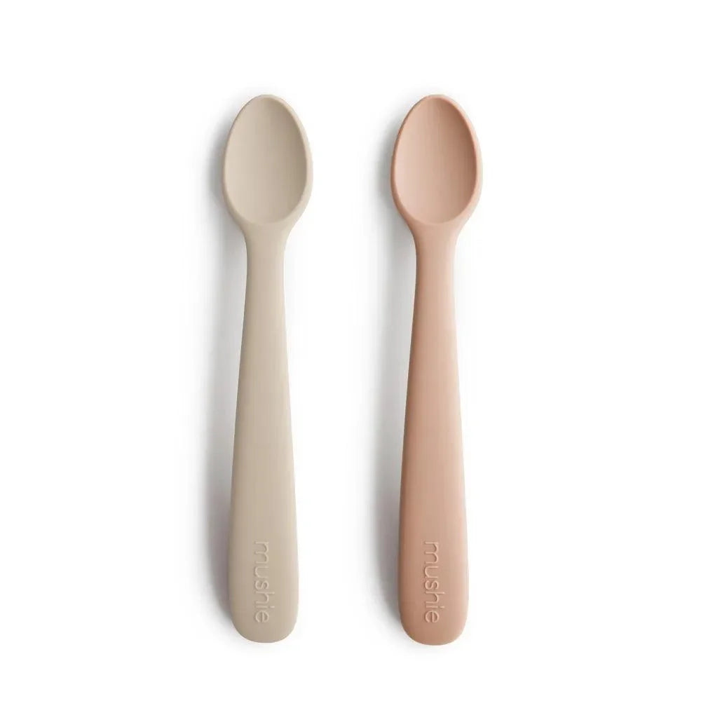 Zwei Baby-Löffel aus Silikon in Beige und Rosa auf weißem Hintergrund