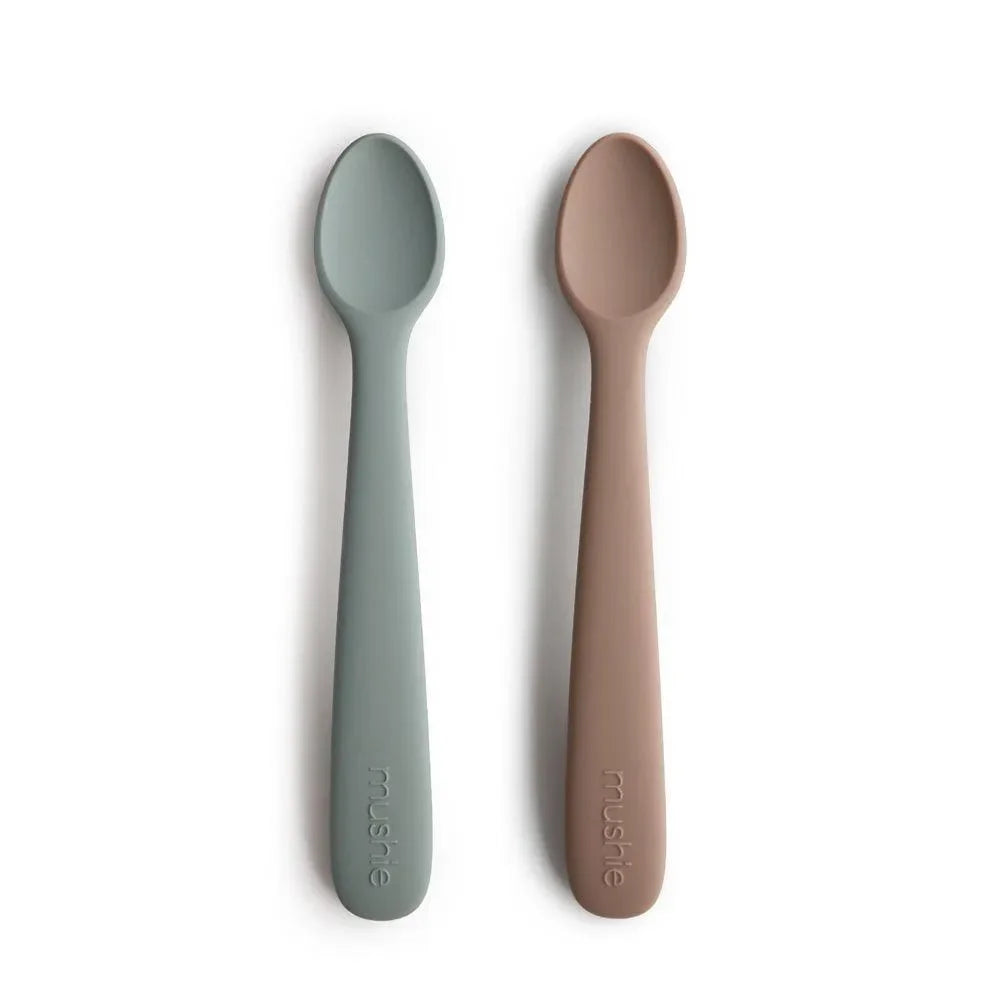 Zwei Baby Löffel aus Silikon in Grau und Mauve, nebeneinander auf weißem Hintergrund.