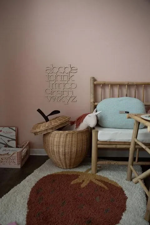 Kinderzimmer mit Holz-ABC-Wanddekoration, Rattanmöbeln und Teppich mit Erdbeermotiv