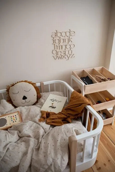 Kinderbett mit Löwenkissen, Holz-ABC-Wanddeko und Spielzeugregal im skandinavischen Stil