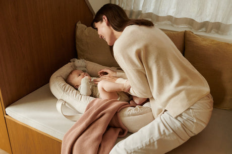 Mutter mit Baby im gemütlichen Babynest auf Sofa, skandinavisches Kinderzimmer bei Nook' d' Mel