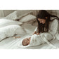 Mutter wickelt ihr Baby auf dem Bett in einer My Memi - Bambus Babydecke / Wickeldecke
